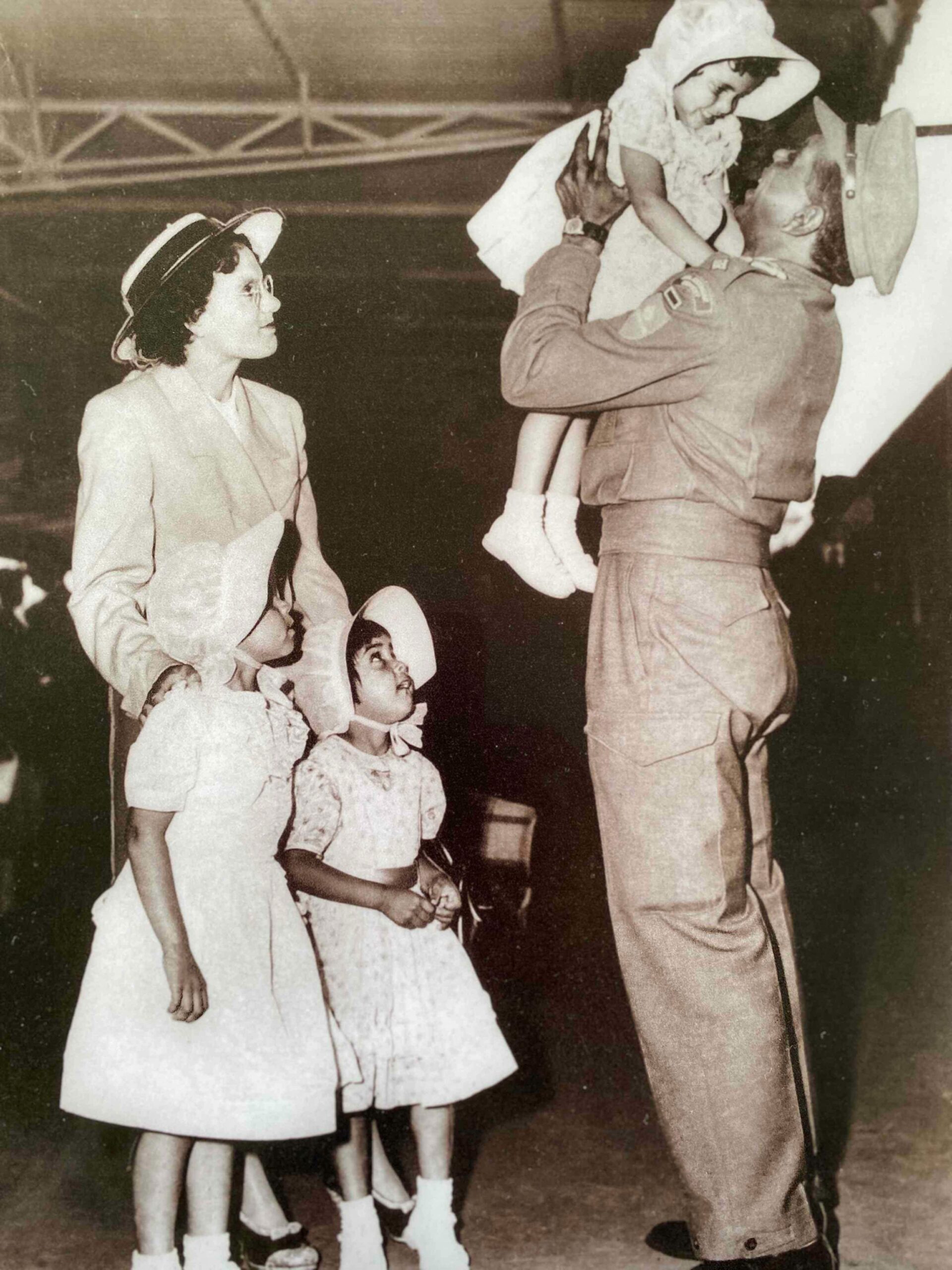 Captain Reginald Saunders MBE arriving home from Korea at Spencer Street Railway Station, with his wife Dorothy and daughters Barbara, Glenda and Dorothy in his arms.
